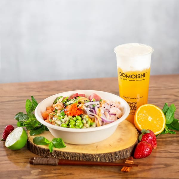 A colorful poke bowl with shrimp, tuna, and vegetables next to a DOMOISHI boba tea.